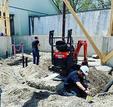 Plumbers excavating ground for a new residential plumbing system installation.